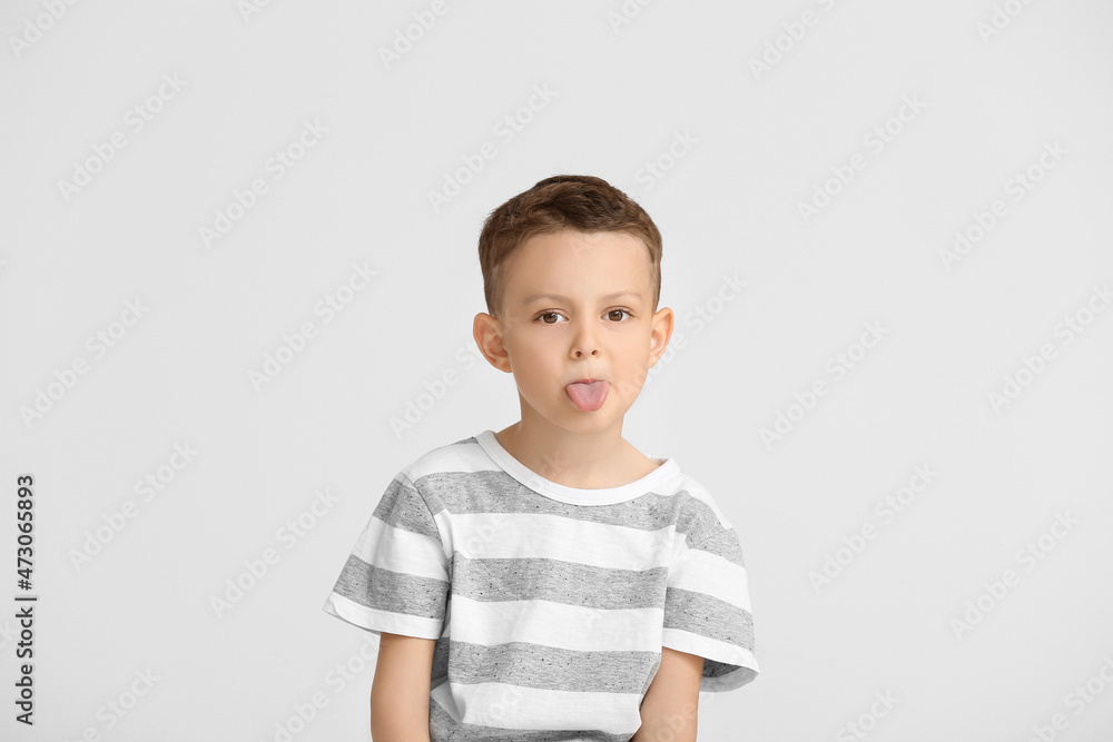 Portrait of cute little boy showing tongue on light background Portrait of cute little boy showing tongue on light background