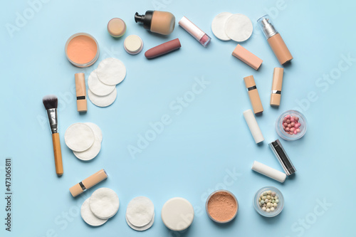 Frame made of different decorative cosmetics and clean cotton pads on color background