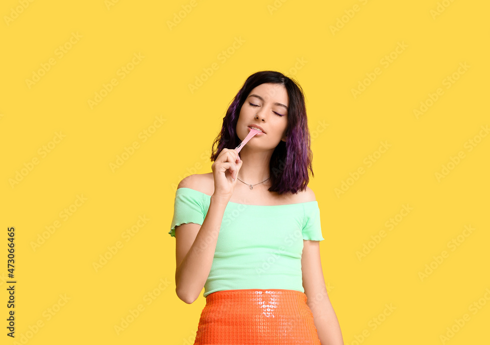 Young woman with purple hair and chewing gum on yellow background Young woman with purple hair and chewing gum on yellow background