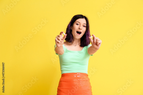 Obraz na plátně Surprised young woman with chewing gums on yellow background