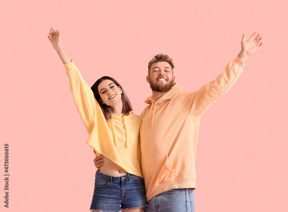Cool happy young couple in hoodies on color background Cool happy young couple in hoodies on color background