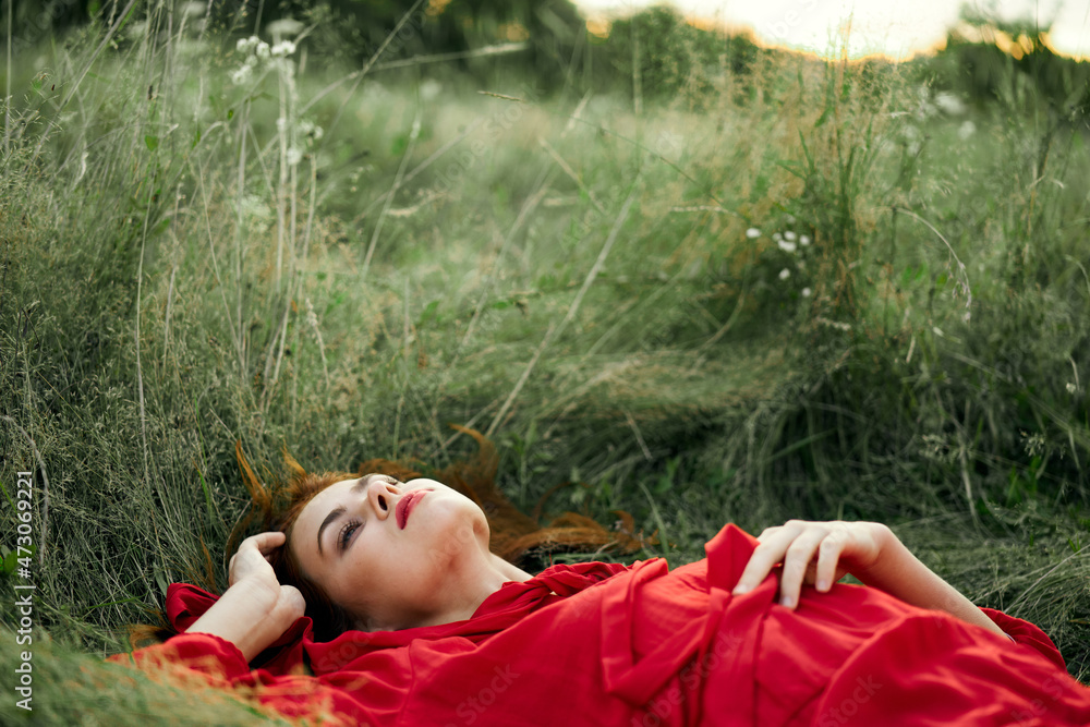 pretty woman in red dress lies on the grass freedom landscape