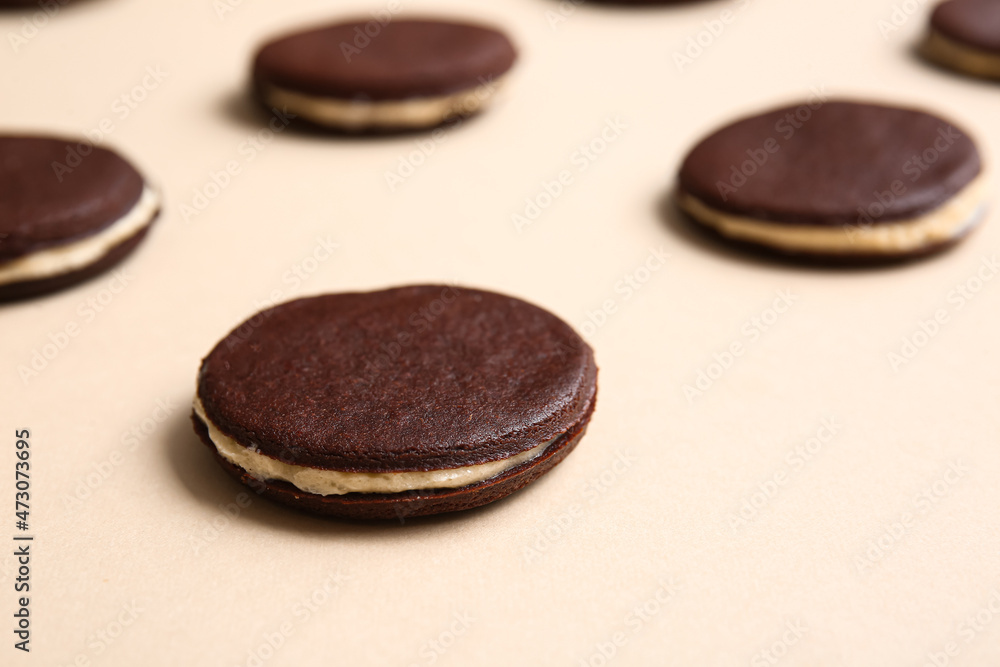 Tasty chocolate cookies with cream on beige background, closeup Tasty chocolate cookies with cream on beige background, closeup