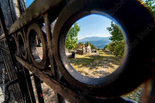 Mountainside Cemetary seen through the hole of an iron fence,central Montenegro,Eastern Europe.