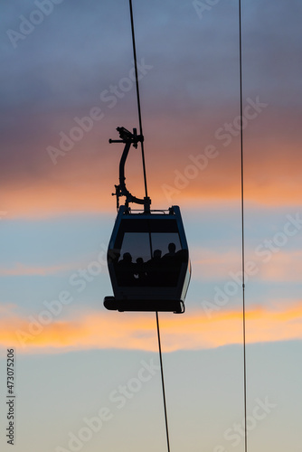 Silhouettes of people in the cabin of the aerial gondola road on a summer evening