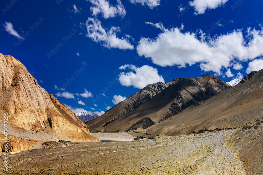 Rocky mountains of Ladakh, fluffy clouds with blue sky, Himalayan mountains in the background, Leh, Jammu and Kashmir, India