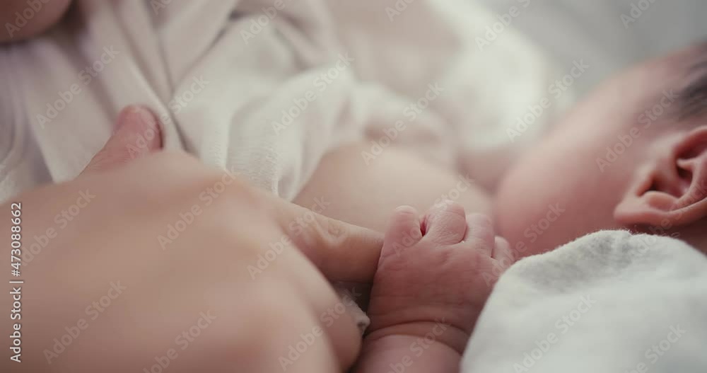 Close up baby hand holding mom fingers, mother breastfeeding newborn baby infant nursing and feeding Baby, feeling love in touch, maternity, healthcare, breastfeeding, motherhood, childhood concept Close up baby hand holding mom fingers, mother breastfeeding newborn baby infant nursing and feeding Baby, feeling love in touch, maternity, healthcare, breastfeeding, motherhood, childhood concept
