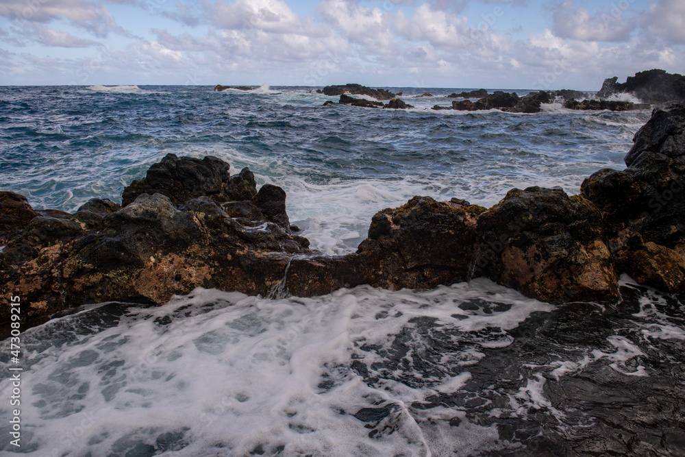 Cooled black lava beaten by the Atlantic ocean waves. View of sea waves hitting rocks on the beach. Waves and rocks.