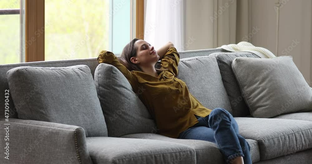 Serene rest. Peaceful young woman recline on soft comfy couch hold hands over head relax lost in dreams breath cool fresh air. Lazy teen female chill meditate at cozy living room enjoy weekend at home Serene rest. Peaceful young woman recline on soft comfy couch hold hands over head relax lost in dreams breath cool fresh air. Lazy teen female chill meditate at cozy living room enjoy weekend at home