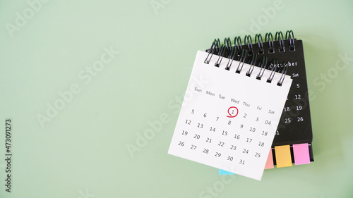 red marked on the 1st day of the month on opened white calendar on black calendar and green background with copy space