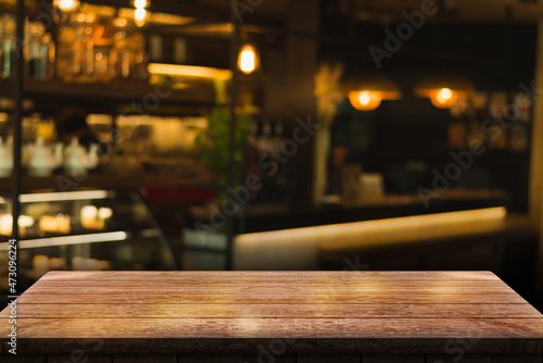 Empty wooden table top with lights bokeh on blur restaurant background.