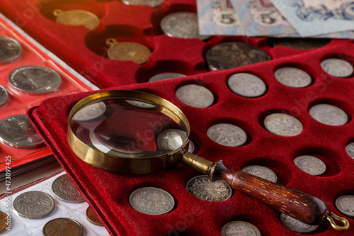 Numismatics. Old collectible coins made of silver on a wooden table.Coins in the album.Collection of old coins. Magnifying glass photo
