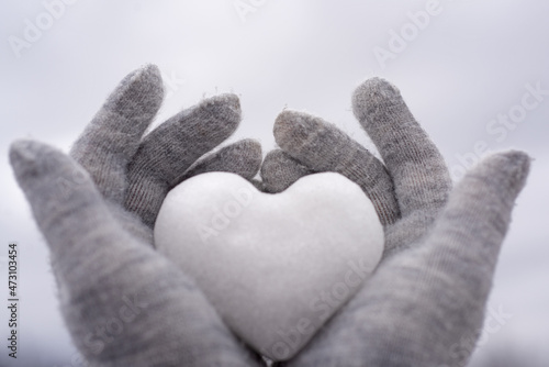 Hands in knitted mittens with heart of snow. Love winter. Valentine day background.