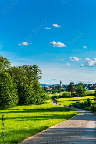 Germany, Beautiful nature landscape view and houses and church of village ostfildern kemnat behind curved way and green fields in summer photo