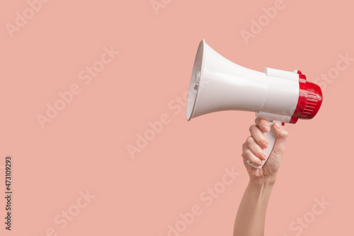 Megaphone in woman hands on a pink background.
