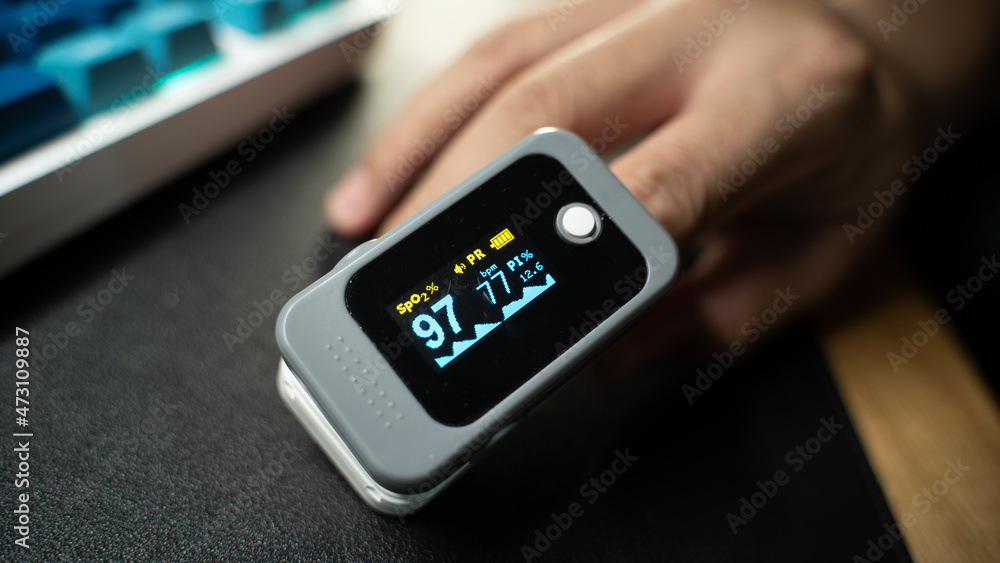 Pulse Oximeter portable digital device to measure person's oxygen saturation. Reduction in oxygenation is an emergency sign, heavy form of Covid-19 viral pneumonia. Device on Caucasian female hand. Pulse Oximeter portable digital device to measure person's oxygen saturation. Reduction in oxygenation is an emergency sign, heavy form of Covid-19 viral pneumonia. Device on Caucasian female hand.