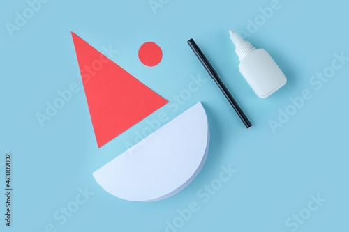 DIY and kid's creativity. Step by step instruction: how to make Santa claus from paper. Step2 cut out cap and circle for Santa's face from paper. Children's Christmas and New year photo