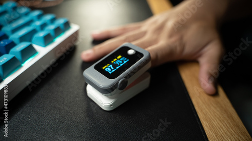 Pulse Oximeter portable digital device to measure person's oxygen saturation. Reduction in oxygenation is an emergency sign, heavy form of Covid-19 viral pneumonia. Device on Caucasian female hand.