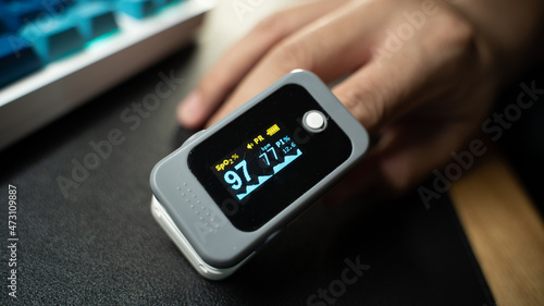 Pulse Oximeter portable digital device to measure person's oxygen saturation. Reduction in oxygenation is an emergency sign, heavy form of Covid-19 viral pneumonia. Device on Caucasian female hand.