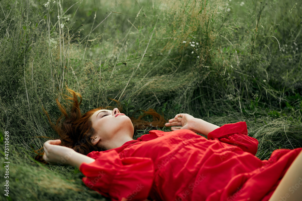 pretty woman in red dress lies on the grass in the field nature fresh air pretty woman in red dress lies on the grass in the field nature fresh air