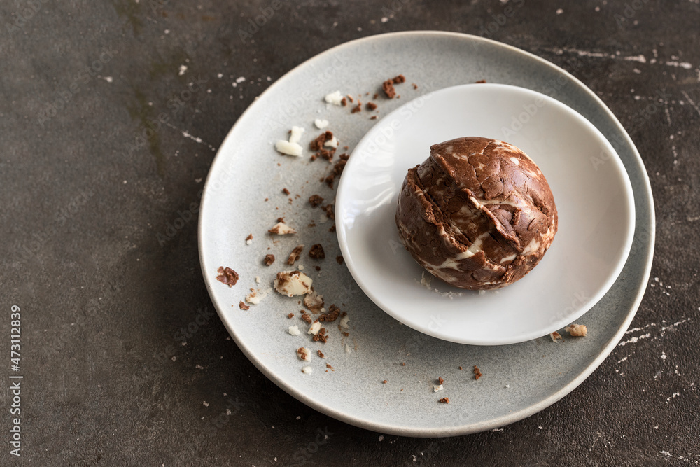 Chocolate vanilla ice cream ball on the white plate on dark background Chocolate vanilla ice cream ball on the white plate on dark background