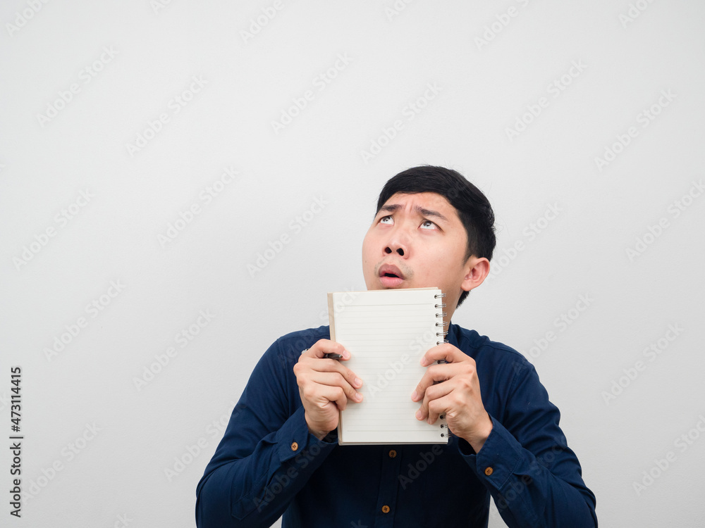 Man holding paper notebook feeling shocked looking up at copy space Man holding paper notebook feeling shocked looking up at copy space