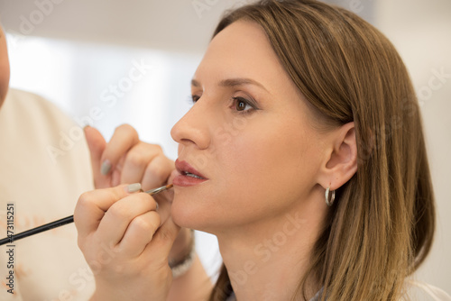 Makeup Artist applies lipstick to a beautiful woman