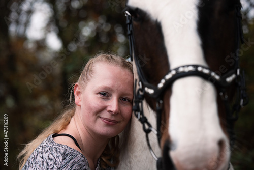 Portrait einer Frau, welche sich an ihr Pferd lehnt