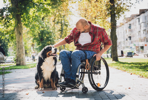 Happy young man with a physical disability in a wheelchair with his dog. © romaset