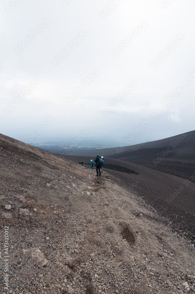Escursionisti scendono tra le rocce del Vulcano Etna