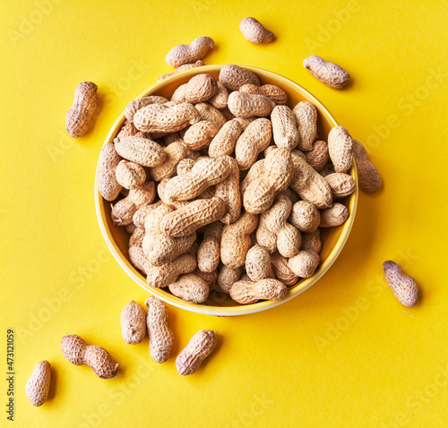  Bowl of peanuts with shell on a yellow background photo