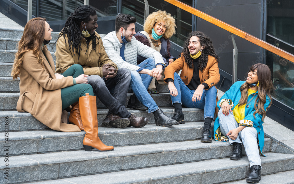 Obraz premium group of friends afro american and caucasian sitting and talking outdoor, people with facmask, social distance and outdoor hangout