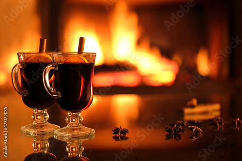 Two glasses with mulled wine on the fireplace background. Romantic concept. Background with text space.