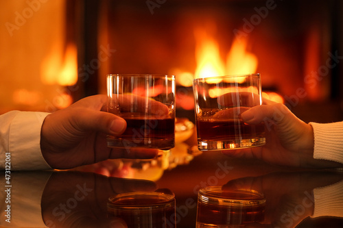 Young couple has romantic dinner with whiskey over fireplace background. Romantic concept.