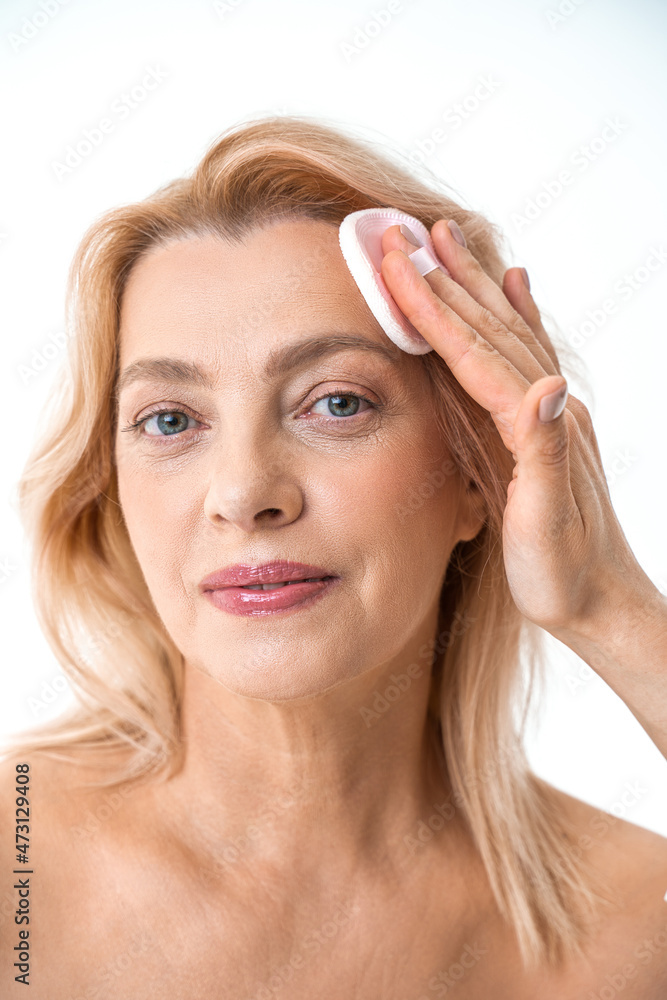 Mature attractive woman cleaning her face with a cotton pad Mature attractive woman cleaning her face with a cotton pad