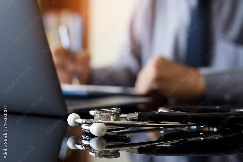 Doctor writing prescription, work on laptop computer at office. Doctor writing prescription, work on laptop computer at office.