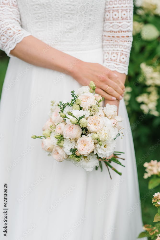 The bride holds her wedding bouquet with white and pink flowers close-up The bride holds her wedding bouquet with white and pink flowers close-up