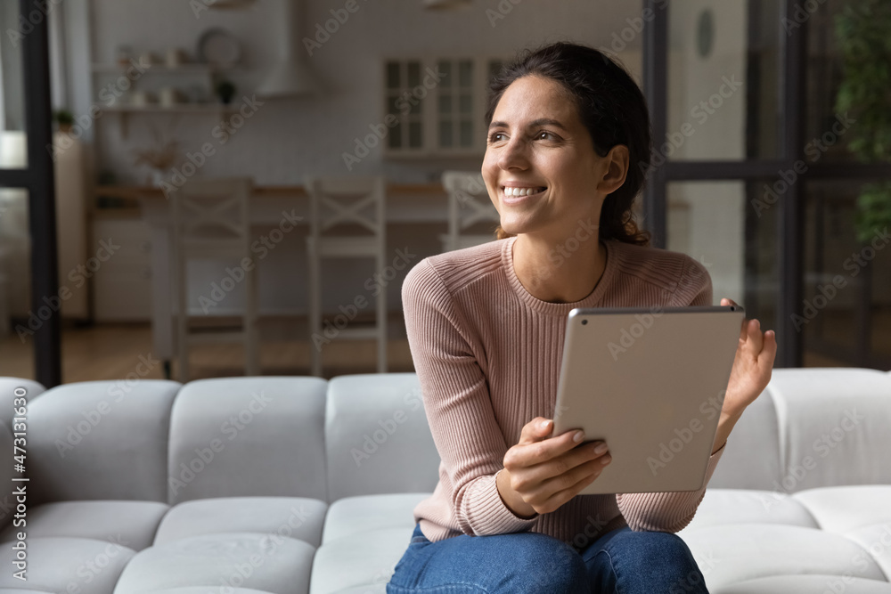 Close up smiling woman distracted from tablet, looking to aside, chatting online with boyfriend or waiting for message, excited young female sitting on couch at home, visualizing good future Close up smiling woman distracted from tablet, looking to aside, chatting online with boyfriend or waiting for message, excited young female sitting on couch at home, visualizing good future