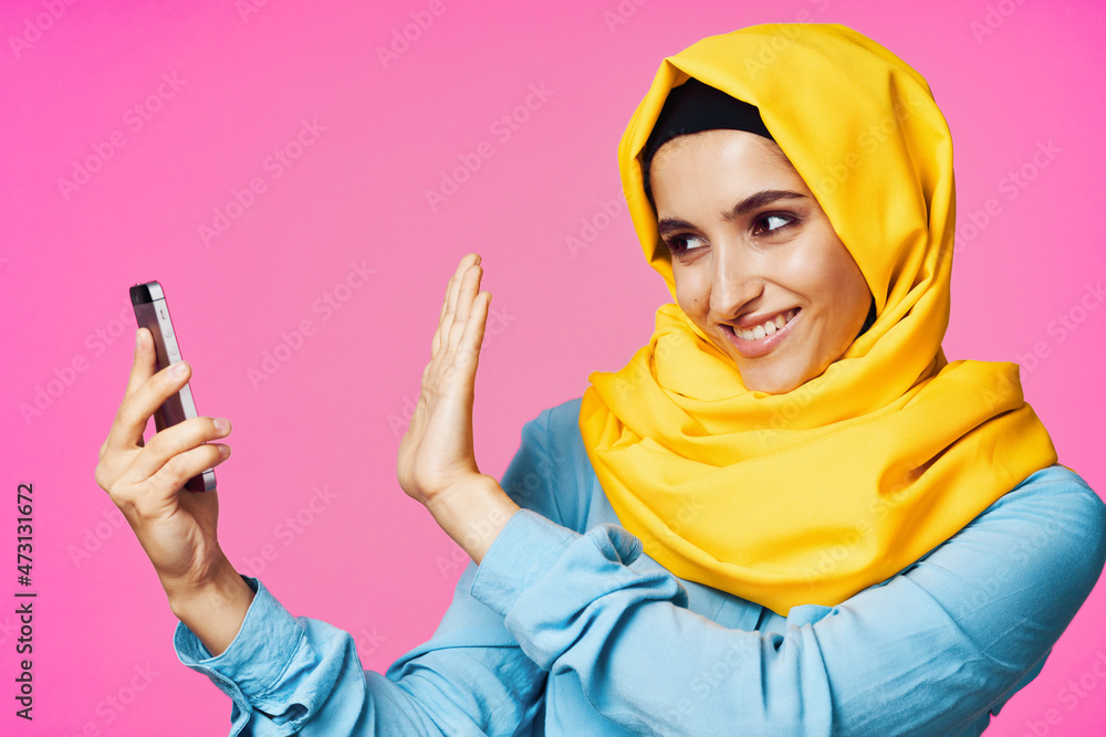 cheerful woman in a yellow hijab with a phone in her hands communication technology cheerful woman in a yellow hijab with a phone in her hands communication technology