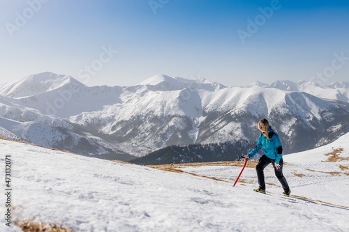 Woman hiker tourist climbing with pickax in snowy winter mountains. Polish Tatra mountains