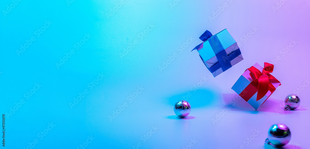 Neon Christmas winter background. Xmas gift box with shine lights. Holiday gifts, decoration bauble ball on neon abstract gradient backdrop. Happy new year copy space. Neon Christmas winter background. Xmas gift box with shine lights. Holiday gifts, decoration bauble ball on neon abstract gradient backdrop. Happy new year copy space.
