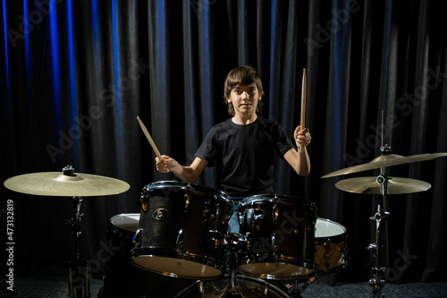 A boy plays drums in a recording studio