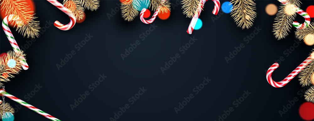 Candy canes with fir branches frame on black background with bokeh lights.