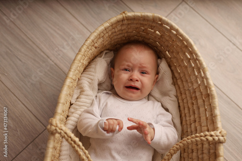 a cute blonde-haired baby in a white suit lies in a straw-woven cradle. a child's dream. high-quality photography