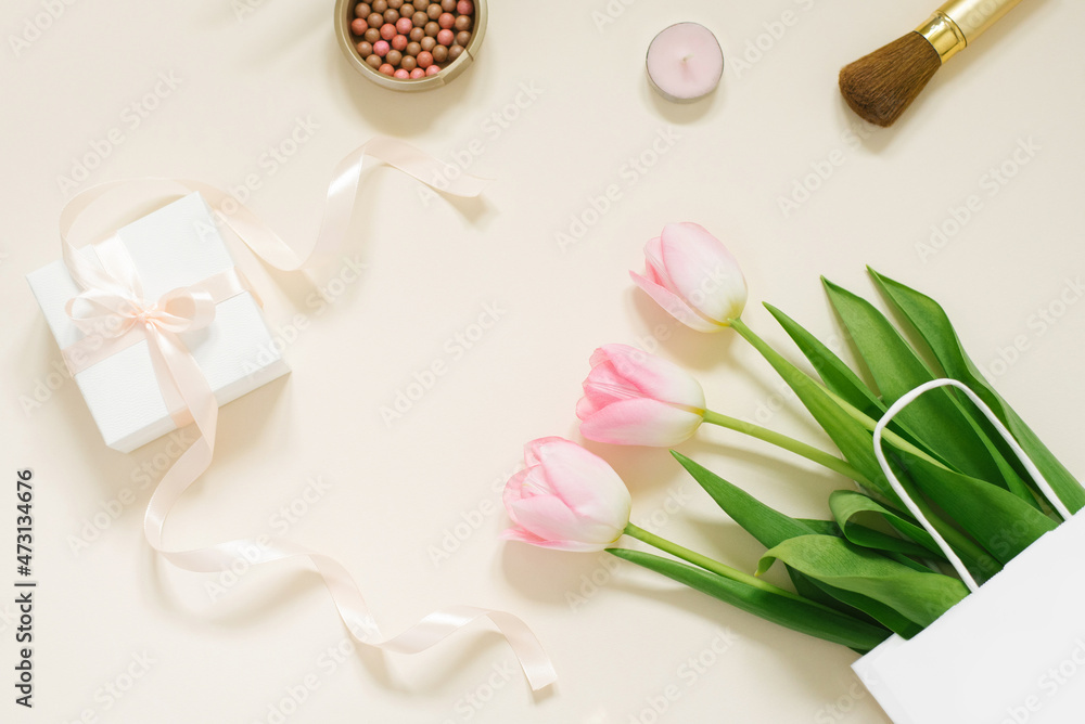 Flat lay composition with cosmetic products for makeup and pink tulips on a beige background Flat lay composition with cosmetic products for makeup and pink tulips on a beige background