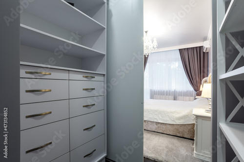 Contemporary bedroom design in a luxurious apartment. Cold tone, painted grey walls, door wardrobe with mirrors. photo