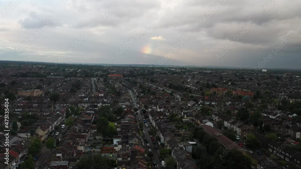 Vast area with low residential houses, rainbow in cloudy sky