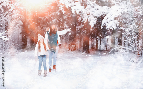 Young family for a walk. Mom and daughter are walking in a winter park.