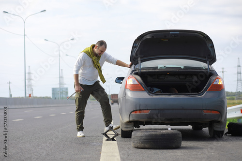 Replacing the wheel of a car on the road. A man doing tire work on the sidelines. © alexkich