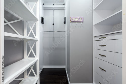 Emplty closet for storing of clothes in brdroom. Shelves and two level clothes rods are built in photo